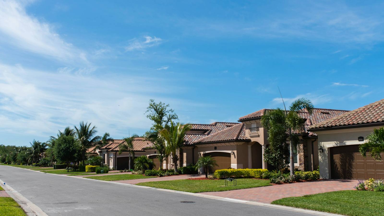 Florida street of tile-roof homes with palm trees under a bright blue sky
