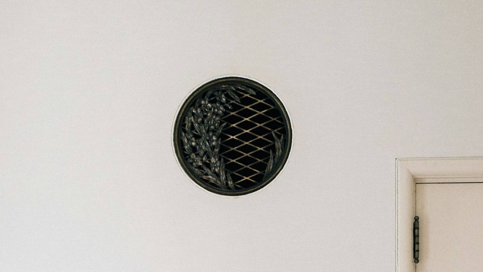 Round decorative air register on a white interior wall